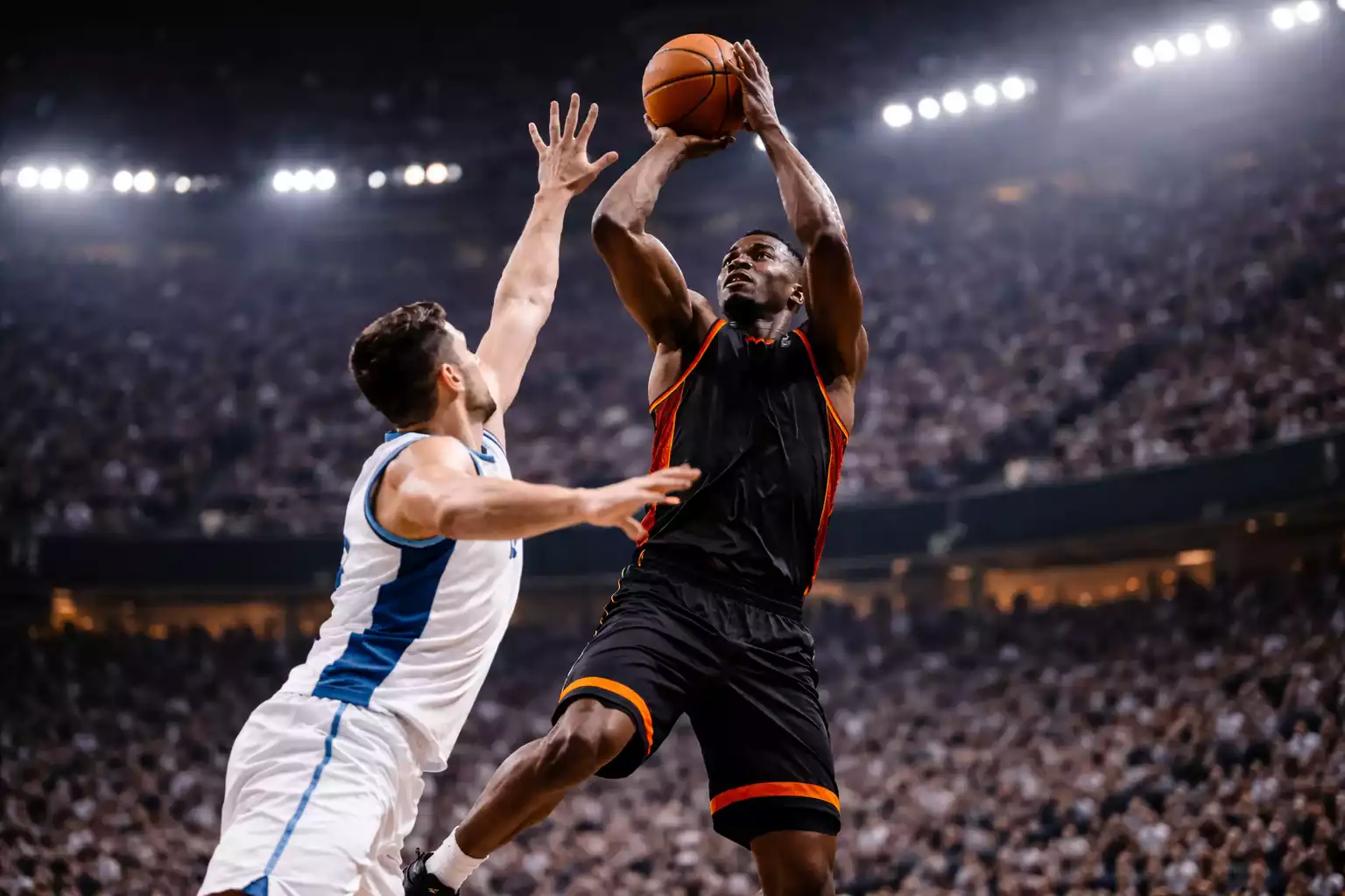 Basketbalspeler springt voor een schot terwijl verdediger blokkeert